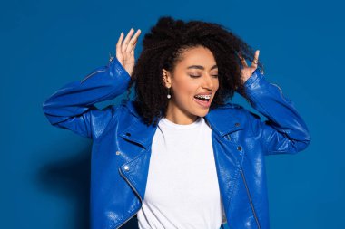 happy african american woman dancing on blue background