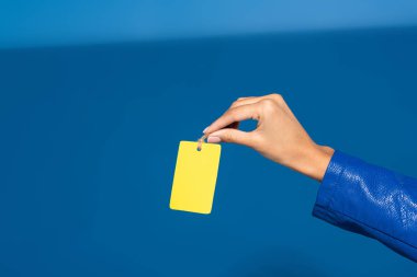 cropped view of african american woman holding yellow empty label on blue background