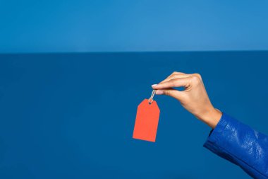 cropped view of african american woman holding red empty label on blue background