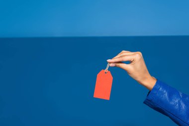 cropped view of african american woman holding red empty label on blue background