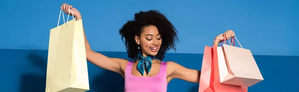 Glimlachende Afro Amerikaanse Vrouw Met Winkeltassen Blauwe Achtergrond Panoramisch Schot — Stockfoto