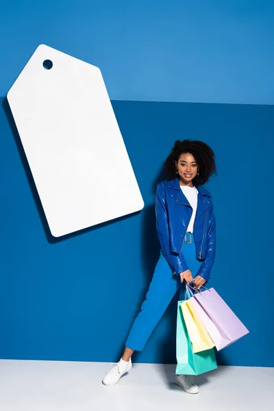 Mosolygós Afro Amerikai Bevásárló Táskák Közelében Nagy Üres Címke Kék — Stock Fotó