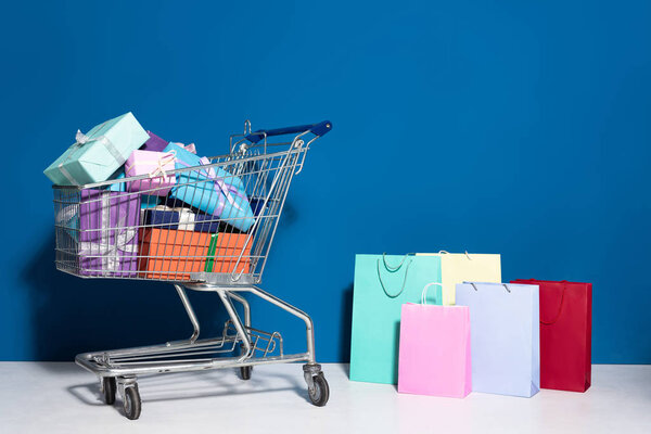 shopping bags, trolley with gifts on blue background