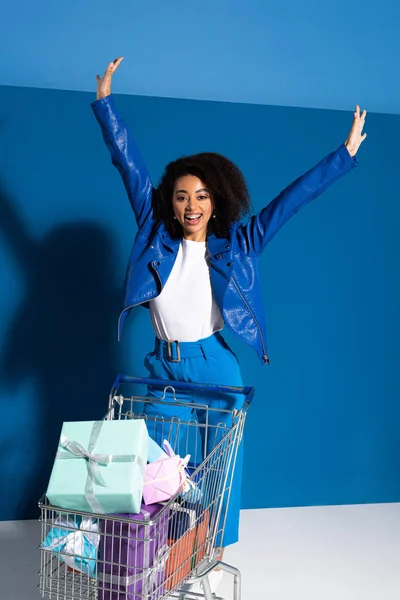 Boldog Afro Amerikai Kezek Levegőben Bevásárlókosár Tele Ajándékokkal Kék Háttér — Stock Fotó