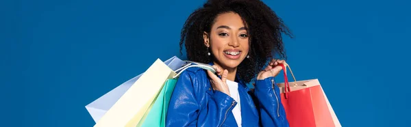 Sorridente Afro Americana Com Sacos Compras Isolados Azul Tiro Panorâmico — Fotografia de Stock