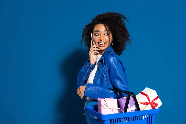 Smiling African American Woman Holding Shopping Basket Gifts Talking Smartphone — 图库照片