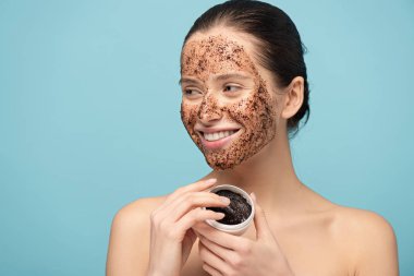 Plastik konteynırdan kahve temizleyen pozitif kız, mavi üzerine izole edilmiş.