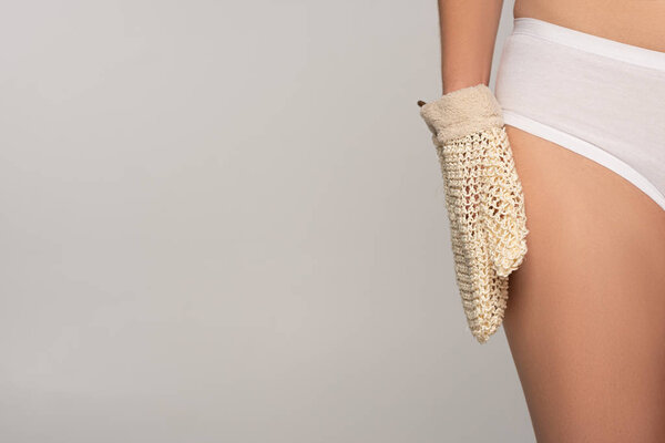 partial view of slim girl with perfect skin holding exfoliation glove, isolated on grey