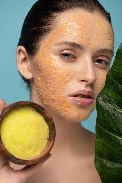 красивая девушка держит сахар скраб в деревянной чаше, изолированные на синий с зеленым листом
