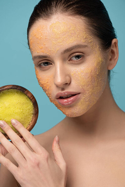 привлекательная молодая женщина держит деревянную чашу с сахаром скраб, изолированный на синий
 