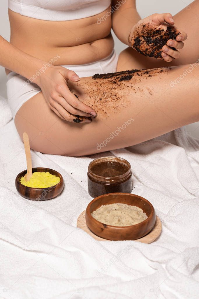cropped view of girl with different scrubs applying coffee scrub on legs