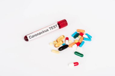 Koronavirüs testinin beyaz harflerle izole edildiği örneklerin yanında renkli haplar. 