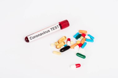 colorful pills near sample with coronavirus test lettering isolated on white  clipart