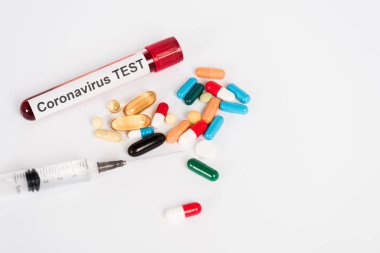 colorful pills near sample with coronavirus test lettering and syringe on white  clipart