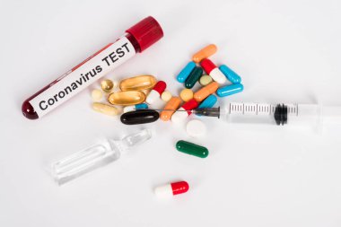 Coronavirüs test harfleri ve beyaz şırınga örneklerinin yanında renkli haplar. 