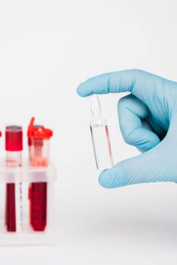 Beyaz test tüplerinin yanında cam şişe tutan bilim adamının kırpılmış görüntüsü. 
