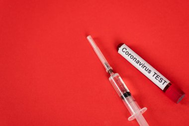 Kırmızı şırınganın yanında Coronavirus test harfleri bulunan numunenin üst görünümü