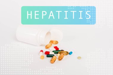 Renkli hapların yanında bir şişe ve beyazın üzerinde hepatit harfleri var.