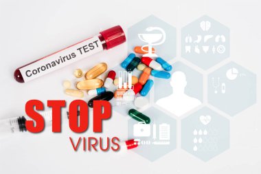 Coronavirüs testi, şırınga ve beyaz harflerle yazılmış virüsü durduran numunenin yanında renkli haplar. 