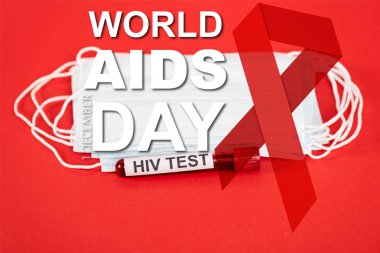 Koruyucu tıbbi maskelerin yanında HIV testi yapılan numune ve kırmızı harflerle Dünya Yardım Günü yazısı. 
