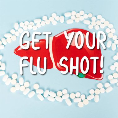top view of pills near drawn liver and get your flu shot lettering on blue  clipart