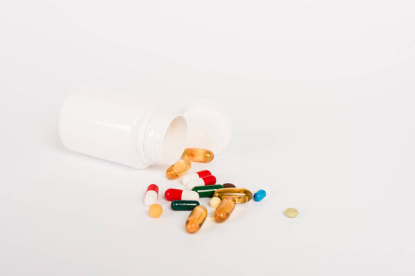 бутылка рядом красочные таблетки на белом с копировальным местом
 