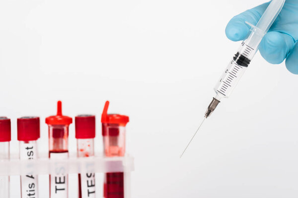 cropped view of scientist holding syringe near test tubes isolated on white 