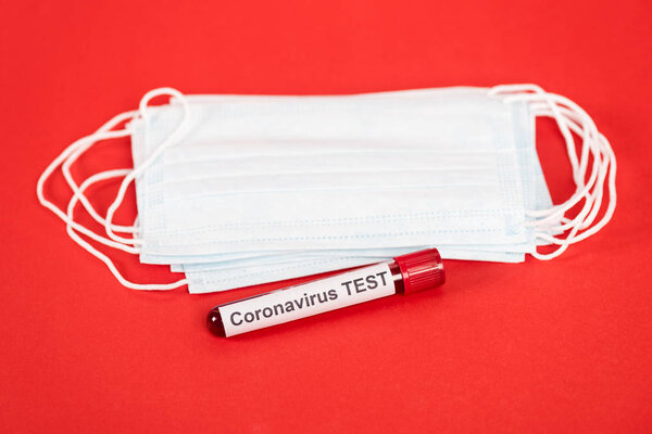 sample with coronavirus test lettering near protective medical masks isolated on red 