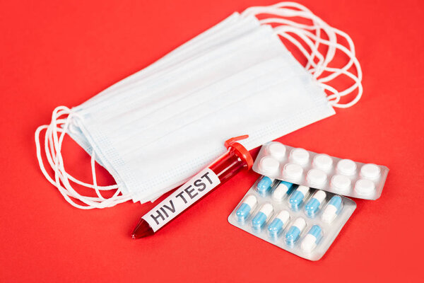 sample with hiv test lettering near pills and medical masks on red 