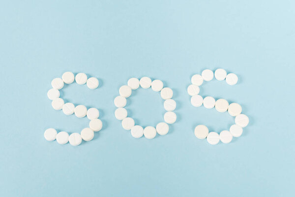 top view of pills with sos lettering on blue 