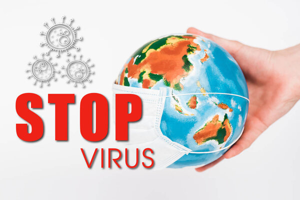 cropped view of man holding globe in protective mask near stop virus lettering on white 