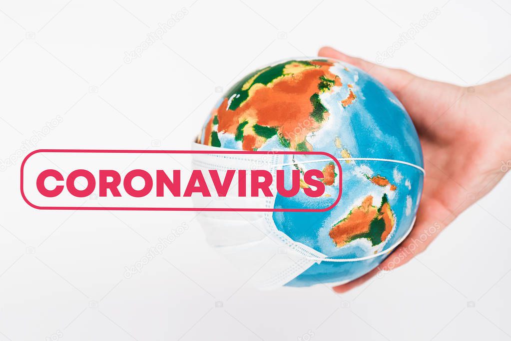 cropped view of man holding globe in protective mask near coronavirus lettering on white 