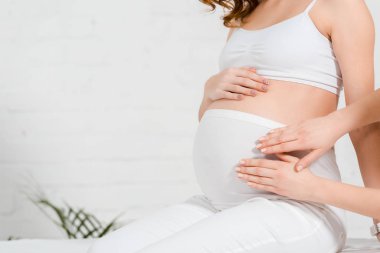 Spa merkezinde masaj yaparken karnına dokunan hamile kadın görüntüsü.