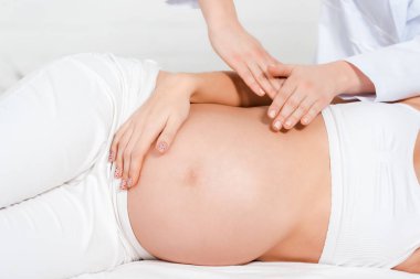Masör, masaj masasında hamile bir kıza masaj yapıyor.