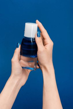 cropped view of woman holding micellar cleansing water isolated on blue clipart