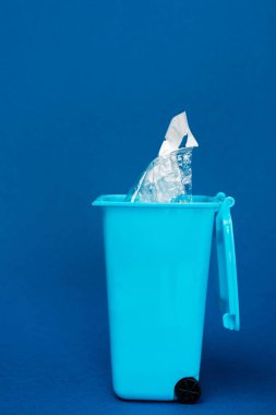 Mavi arka planda plastik poşeti olan oyuncak çöp kutusu. 