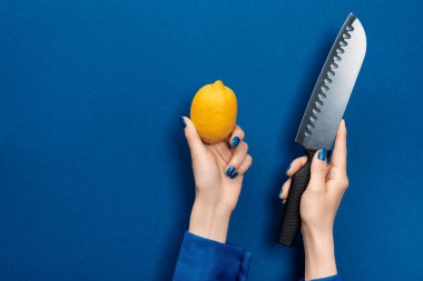 Mavi arka planda limon ve bıçak tutan kadın manzarası 