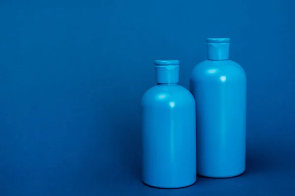 コピースペース付きの青い背景にシャンプー付きのペットボトル — ストック写真