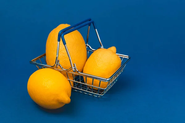 Mavi Arka Planda Bütün Organik Limonlarla Dolu Alışveriş Sepeti — Stok fotoğraf