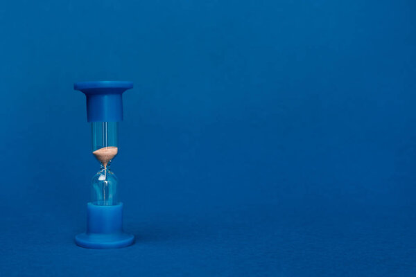 bright and colorful hourglass on blue background with copy space 