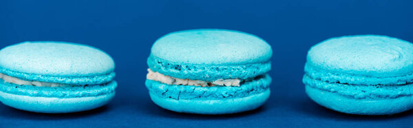 panoramic shot of french macaroons on blue background 