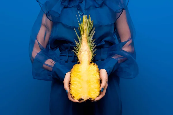 青い背景にカットパイナップルを持つ女性のクロップドビュー — ストック写真