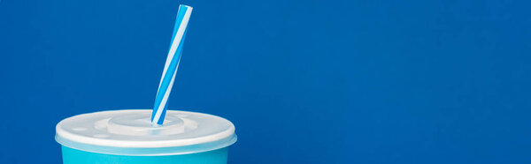 panoramic shot of paper cup with soda isolated on blue