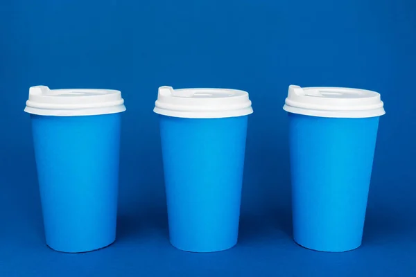 paper cups with coffee on classic blue background