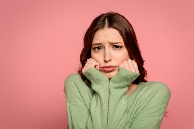 Alıngan kız pembe üzerinde el ele tutuşurken kameraya bakıyor.