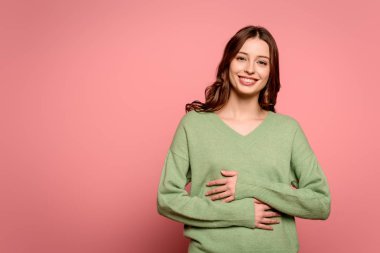Heyecanlı kız pembe arka planda el ele tutuşurken gülüyor.