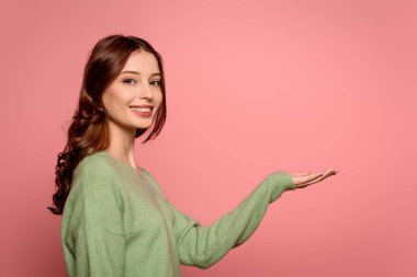 Kolları açık pembe bir şekilde kameraya gülümseyen neşeli kız.