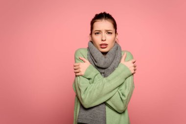 diseased girl in warm scarf hugging herself while having fever isolated on pink clipart