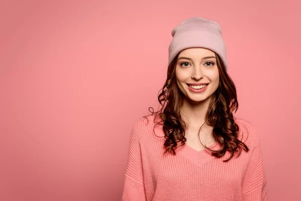 セーターに身を包んだ魅力的な陽気な女の子とピンクに囲まれたカメラで微笑む帽子 — ストック写真