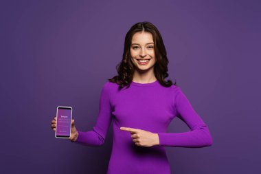 Kyiv, Ukrayna - 29 Kasım 2019: Mor arkaplanda Instagram uygulaması ile akıllı telefonu gösteren gülümseyen kız
